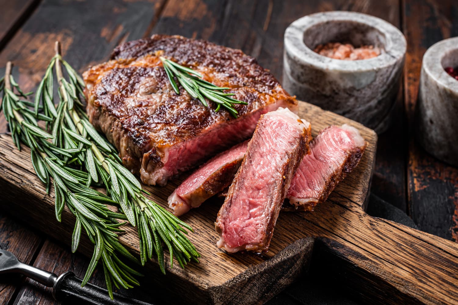 Corte Ribeye Angus premium de Cortes Celorio con romero fresco sobre tabla rústica, carne asada gourmet mexicana de alta calidad.